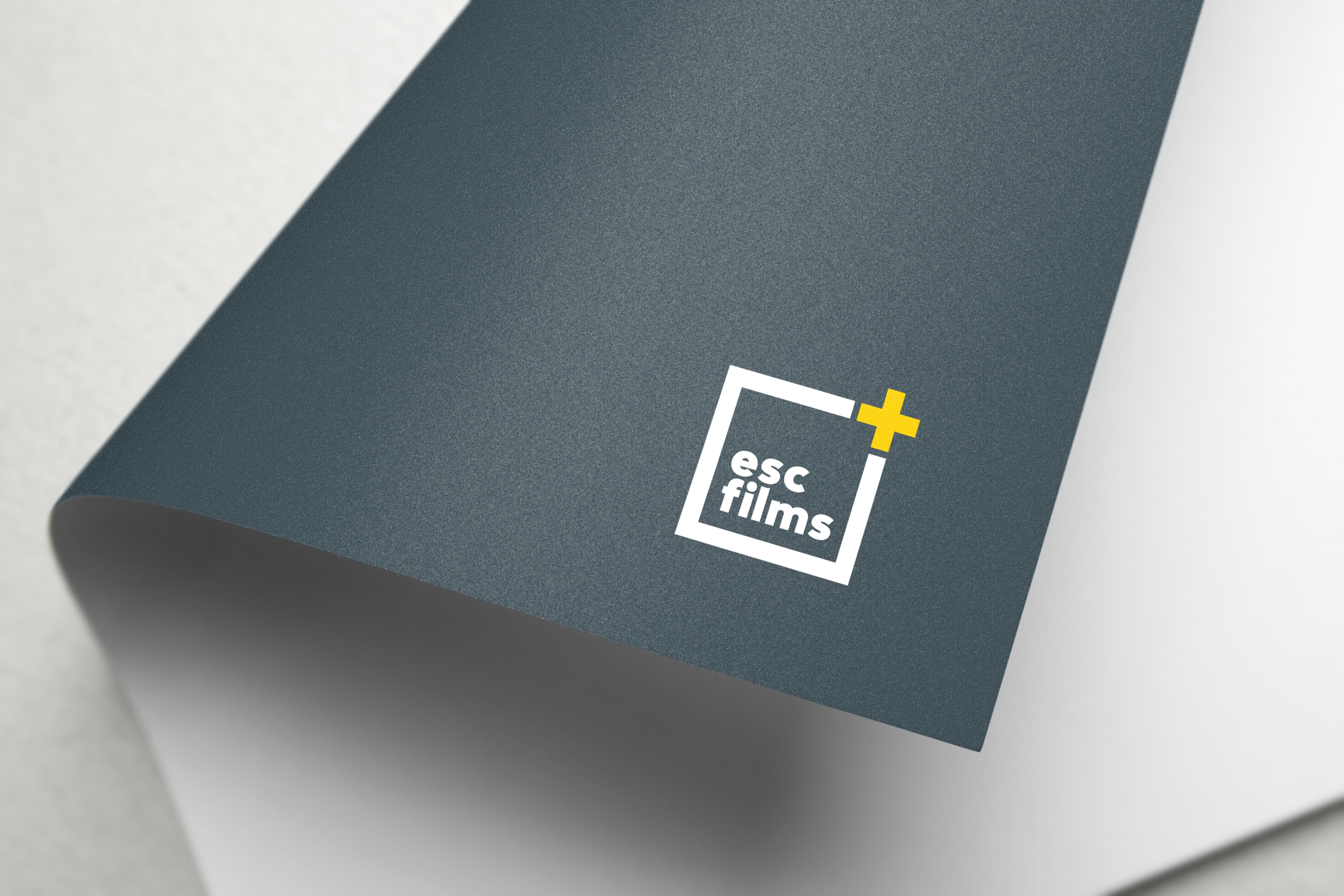 grey rolled up letter with esc films logo in white square with yellow plus sign at top right corner